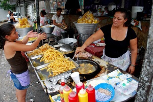 A girl helps her mother run a French fry grill